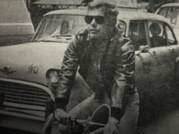 Black-and-white photo of Ralph Lauren on bicycle in city street.